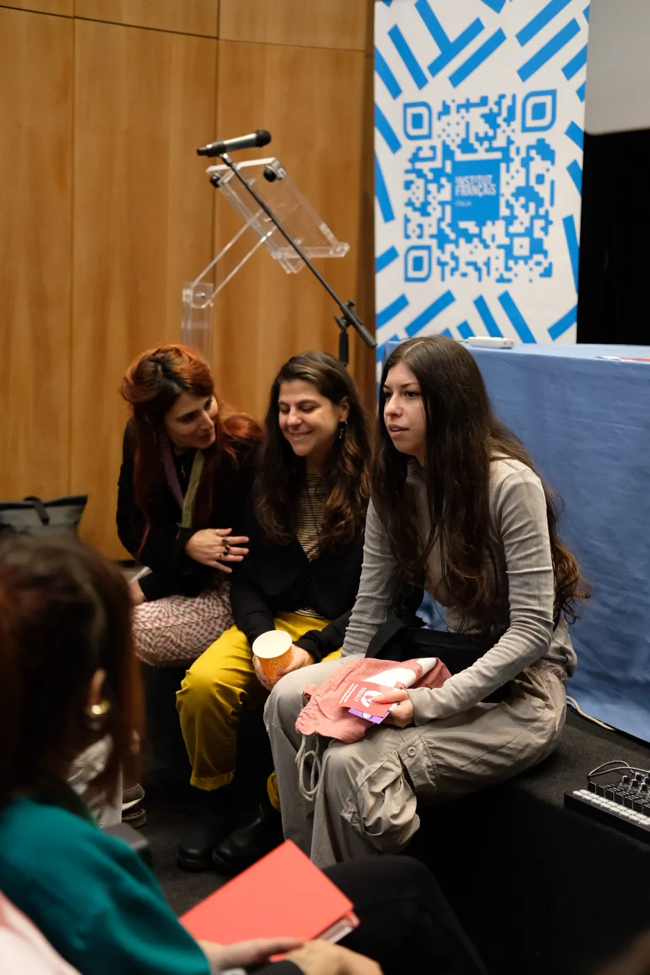 Tre partecipanti sedute durante un incontro, sullo sfondo il banner dell'Institut français