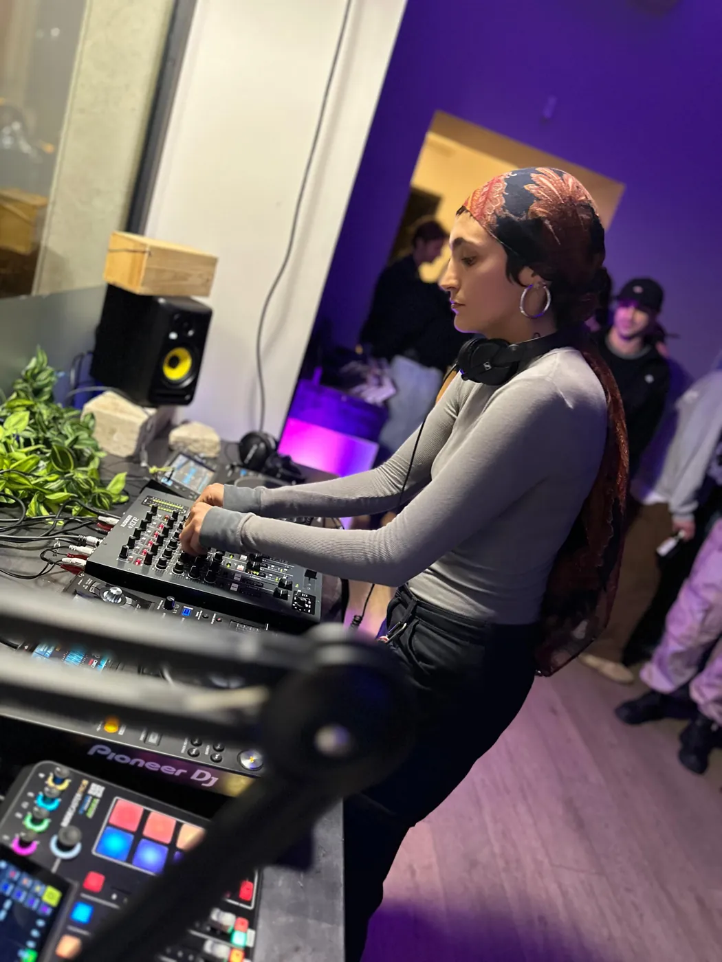 Una DJ con foulard al mixer in uno studio illuminato di viola