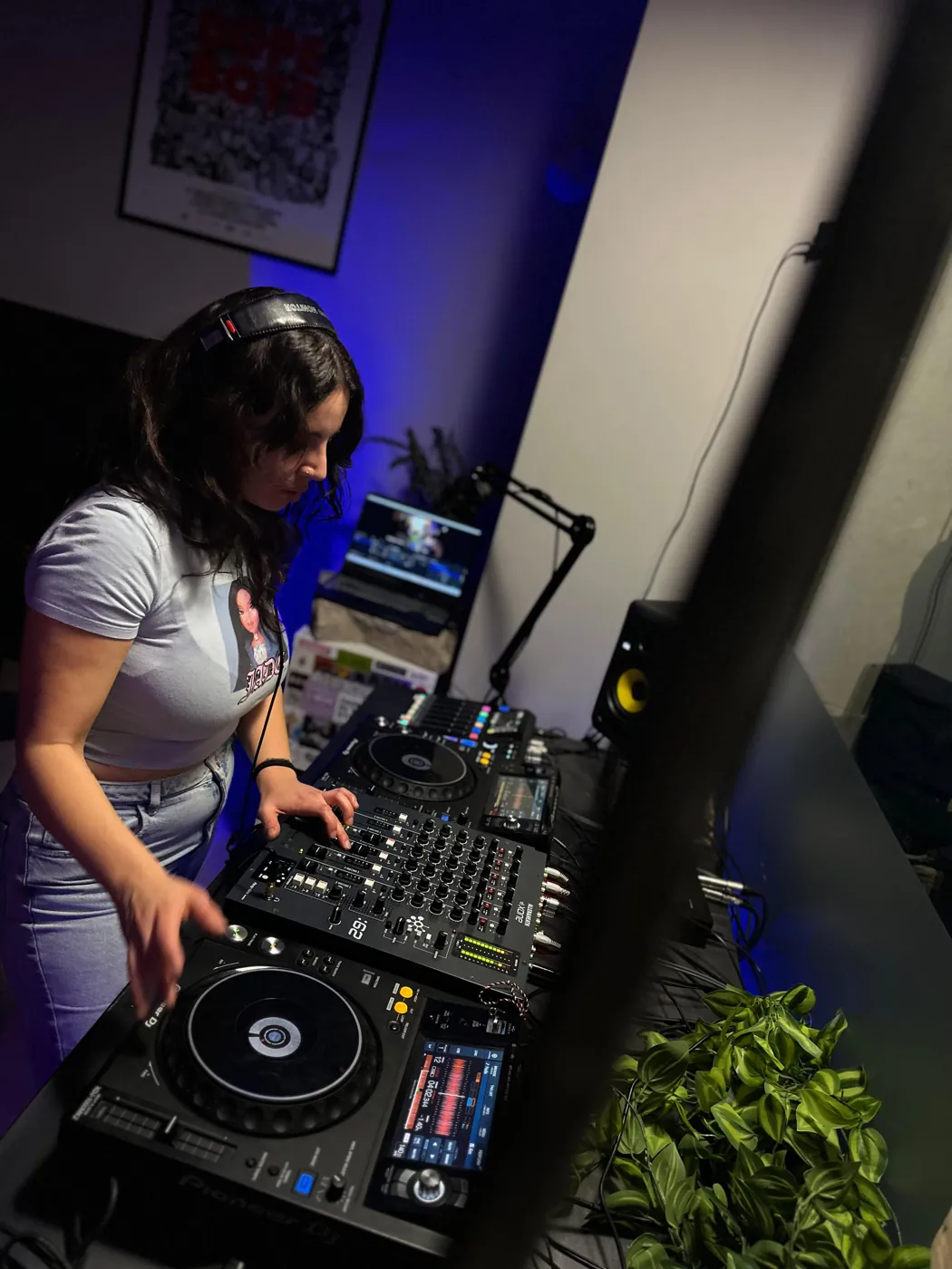 Una DJ con le cuffie ai CDJ in studio, luce blu