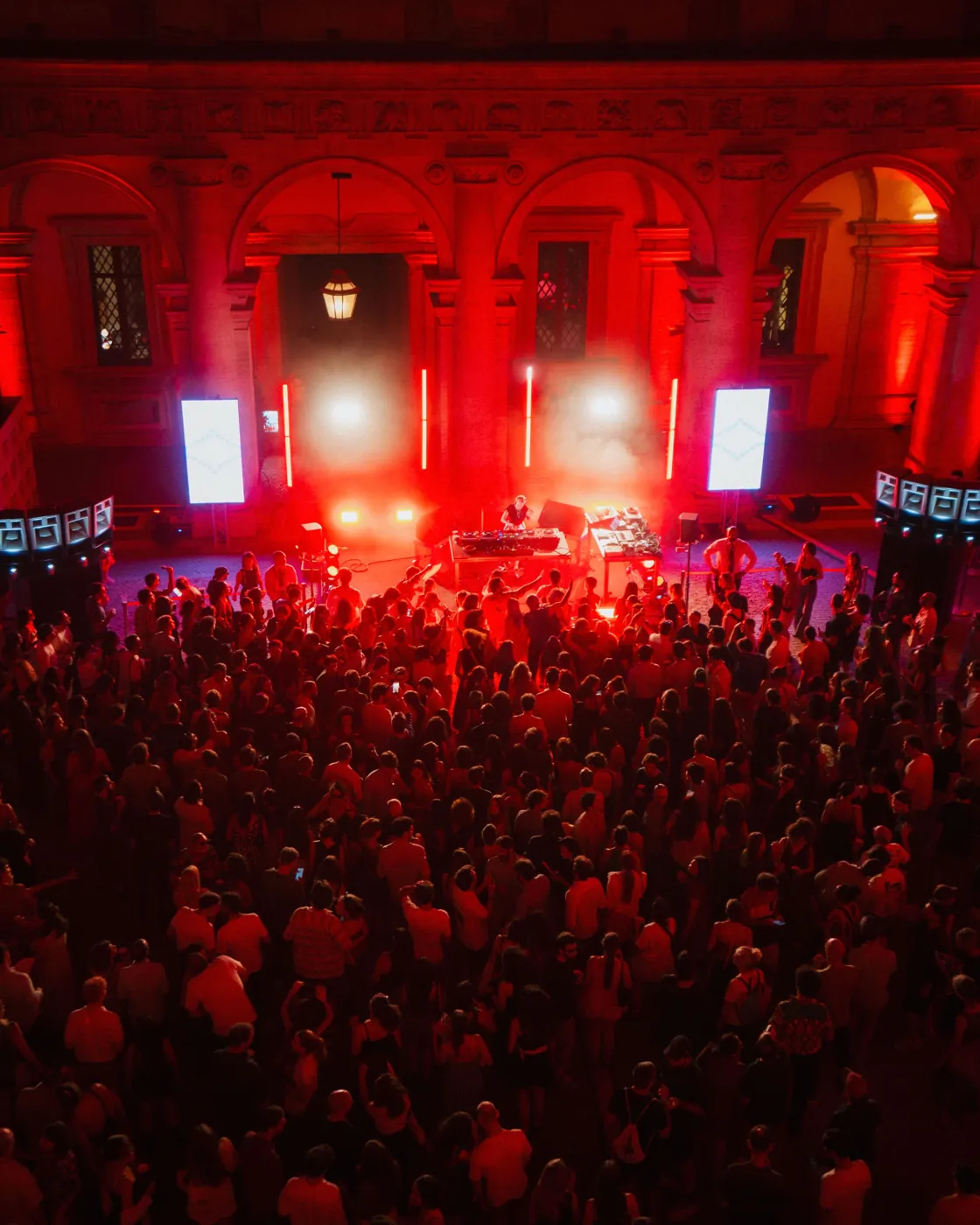 Il cortile di Palazzo Farnese illuminato di rosso, folla davanti alla consolle