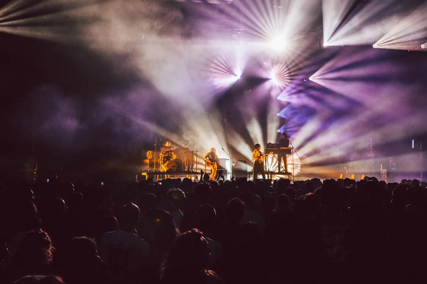 Una band sul palco tra fasci di luce viola e fumo
